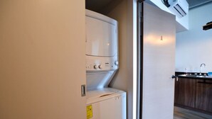 A laundry room with a washer and dryer, a small cabinet, and a kitchen area with a sink and countertop. - ¡Alberca y Gym! / Barrio W / 2 personas #Centro (Monterrey)