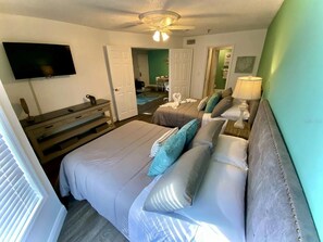 A bedroom with two beds, a TV, a ceiling fan, and a bathroom visible through an open door. - Two bed condo in Parkway Palms Resort mins to Disney World. (Kissimmee)