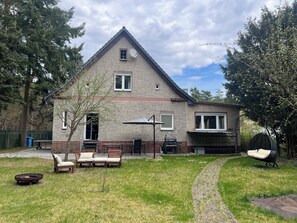 Une maison à deux étages avec une façade en briques, une antenne parabolique, une cheminée et une allée pavée.