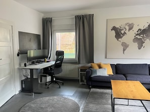 Una sala de estar moderna con un escritorio, computadora y un gran mapa del mundo en la pared.
