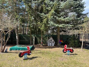 Aidattu ulkoalue, jossa on pieni leikkimökki, keinuteline ja rengaskeinu.