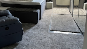 Ein Schlafzimmer mit Bett, Nachttisch, Lampe und Blick ins Freie.