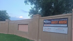 A guest house sign with amenities like high-speed Wi-Fi, spacious room, free parking, and 24/7 security. - Pilgrims Corner Guest House  (Westonaria)