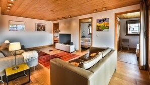 A modern living room with a wooden ceiling, a sofa, a television, and artwork on the walls. - Wifi, 2nd floor, terrace, tv, ski locker, 83m², Les Gets (Les Gets)