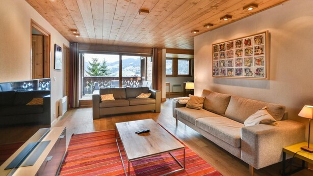 A spacious living room with a wooden ceiling, a sofa set, a coffee table, and a large window offering a view of the outdoors. - Wifi, 2nd floor, terrace, tv, ski locker, 83m², Les Gets (Les Gets)