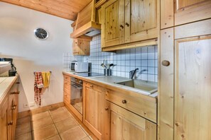 Eine Küche mit Holzausstattung, einer Mikrowelle, einem Spülbecken und einer Uhr an der Wand.
