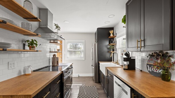 A modern kitchen with wooden countertops, black cabinets, and a checkered floor. - Stylish + Trendy Home W/ Office Near It All! (Indianapolis)