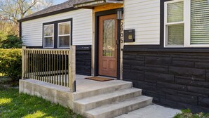A two-story house with a front porch, a wooden door, and a mailbox. - Stylish + Trendy Home W/ Office Near It All! (Indianapolis)