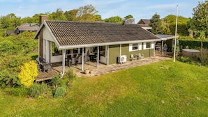 Einbungalow mit überdachter Terrasse, Schornstein und Garten.