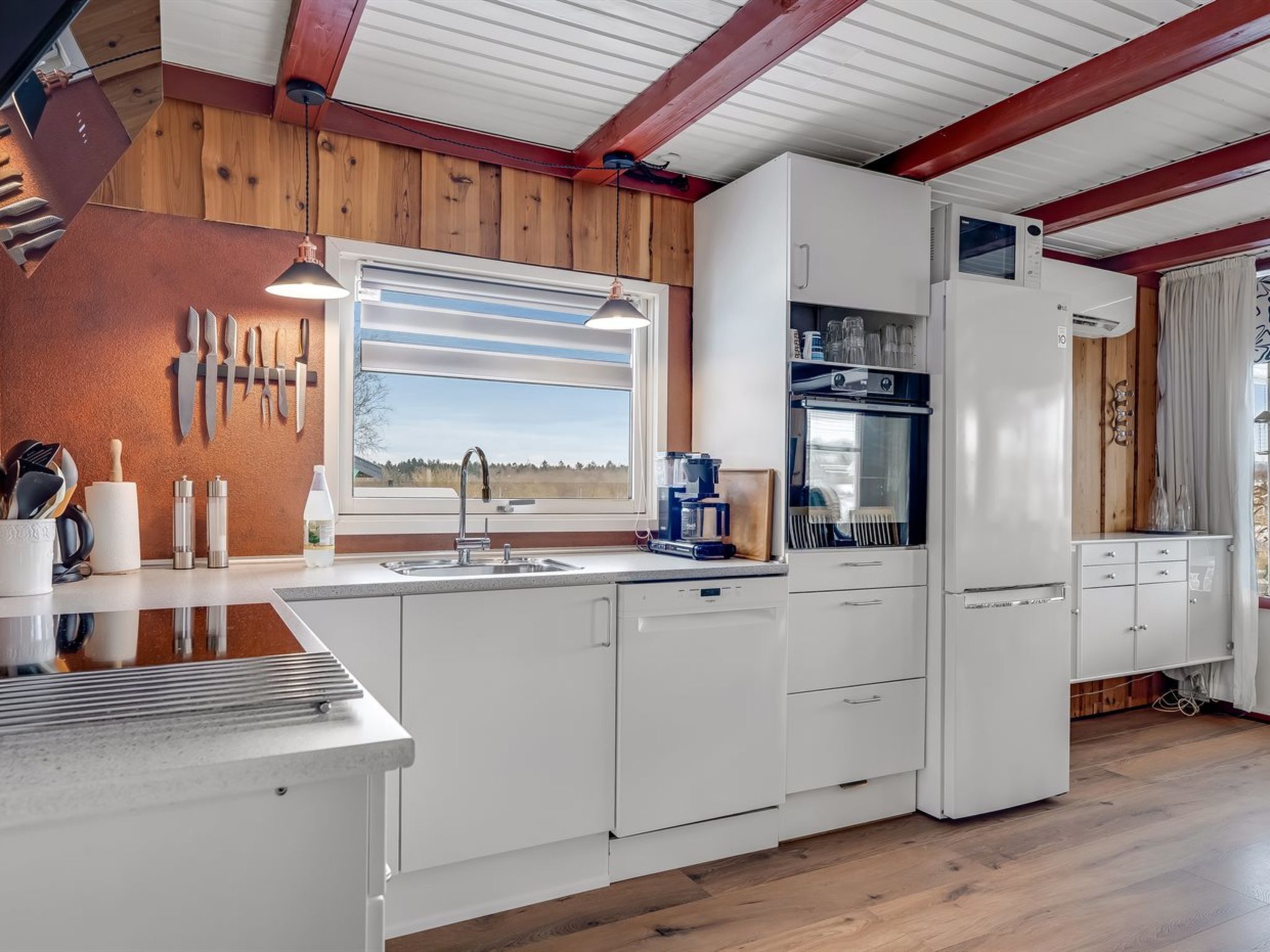 A modern kitchen with white cabinetry, a built-in oven, and a window with a view of the outdoors.