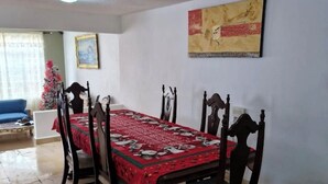 Ein Essbereich mit Tisch für vier Personen, einem gerahmten Bild an der Wand und einem blauen Sofa im Hintergrund.