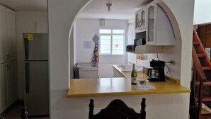 Eine Küche mit Kochinsel, Kühlschrank, Schränken und einem Fenster mit Blumendekoration.