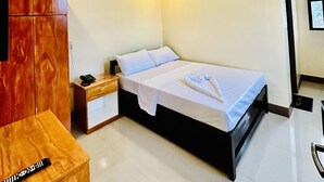 Una camera d'albergo con un letto, un armadio in legno, un comodino e un condizionatore d'aria.
