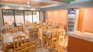 Un restaurante con varias mesas, sillas, un refrigerador y una barra.