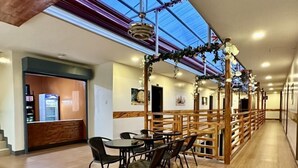 Un vaste espace intérieur doté d’un comptoir d’accueil en bois, d’un long couloir avec des rampes en bois et d’un plafond vitré.