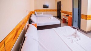 Ein Hotelzimmer mit zwei Betten, einem Fernseher, einem Schreibtisch und einer Tür.