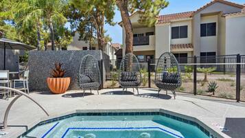 A swimming pool with a tiled edge, surrounded by outdoor seating and a decorative wall.