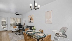 A modern dining area with a glass table, brown chairs, and a white ceiling fan.