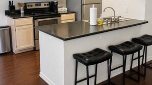 Una cocina moderna con una isla central, electrodomésticos de acero inoxidable y armarios de madera.