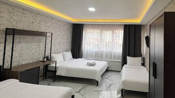 A hotel room with two beds, a desk, a wardrobe, and a large window with curtains.