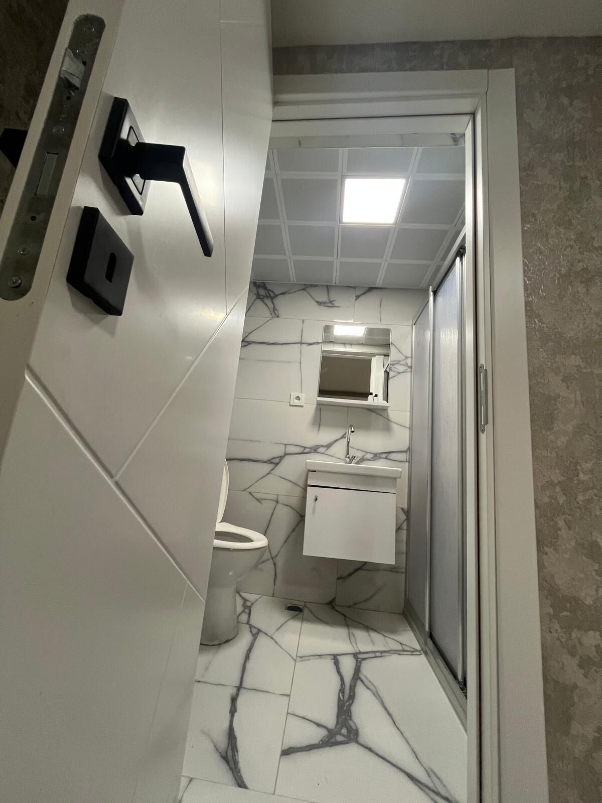 A bathroom with a toilet, sink, and mirror.