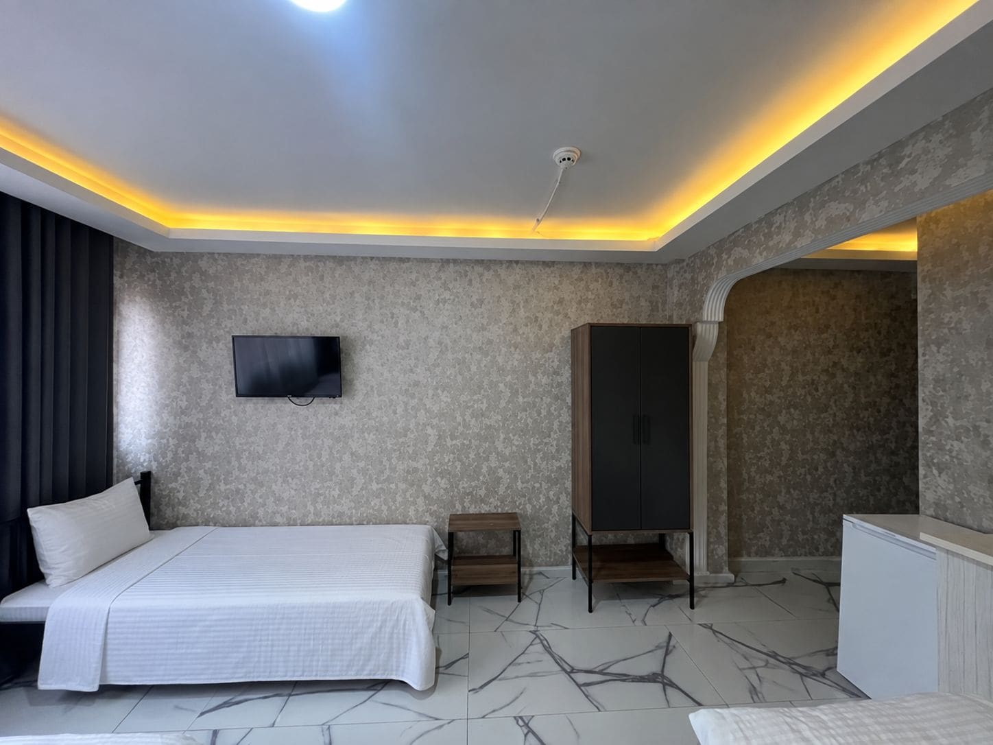 Une chambre d’hôtel moderne équipée d’un lit, d’un téléviseur à écran plat, d’une armoire et d’une coiffeuse.