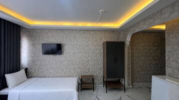 Une chambre d’hôtel moderne équipée d’un lit, d’un téléviseur à écran plat, d’une armoire et d’une coiffeuse.
