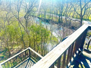 Une terrasse en bois offrant une vue sur une rivière et les arbres environnants.