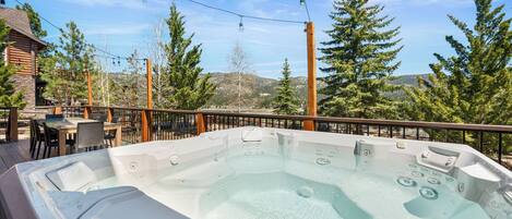 Un jacuzzi en una terraza con vista a la montaña, rodeado de árboles.