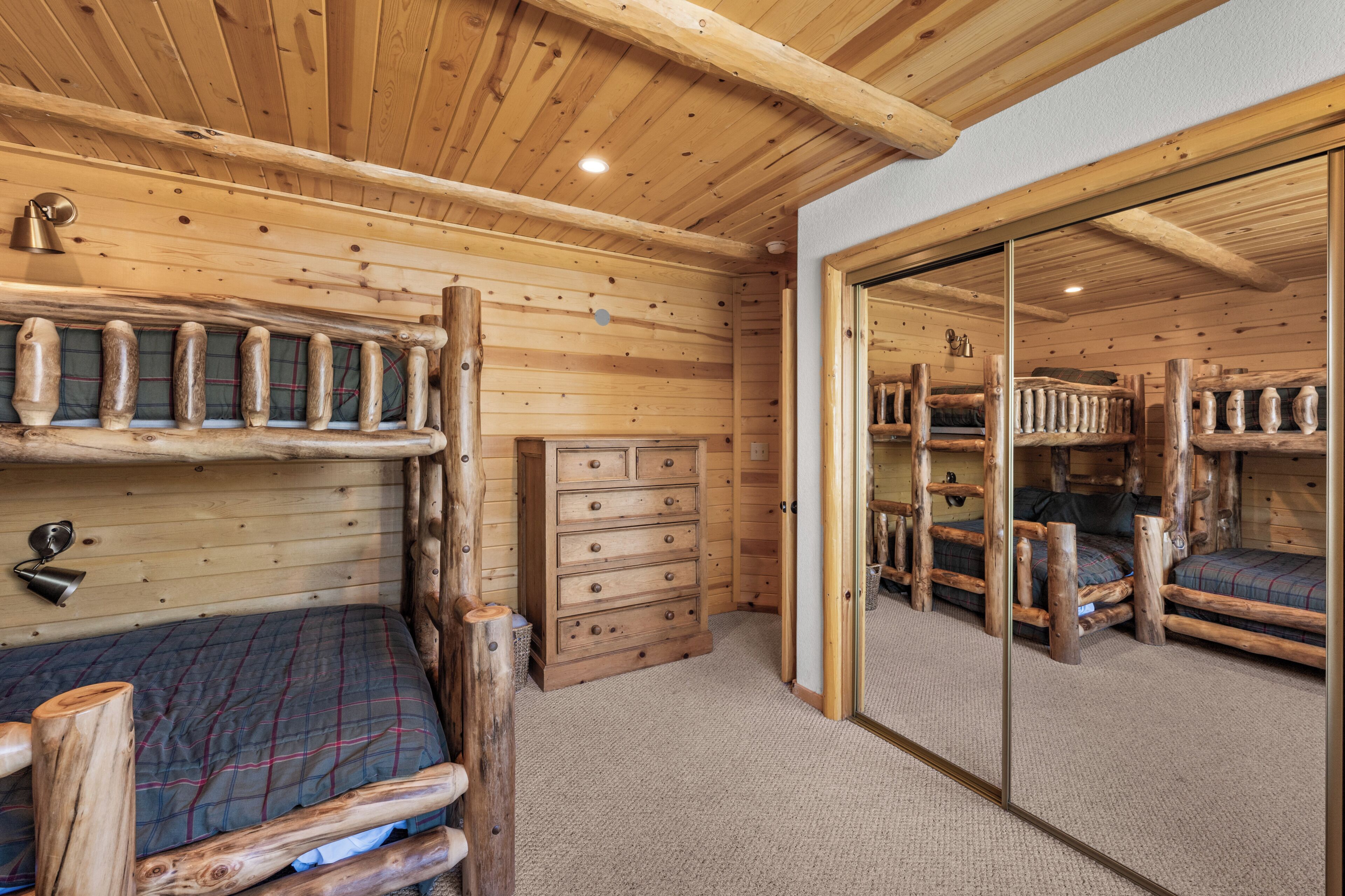 Eine Holzhütte mit Etagenbett, Kommode und Spiegel.