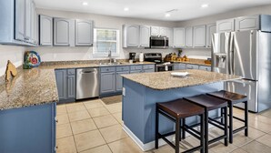 Una cocina moderna con encimeras de granito, electrodomésticos de acero inoxidable y armarios azules.