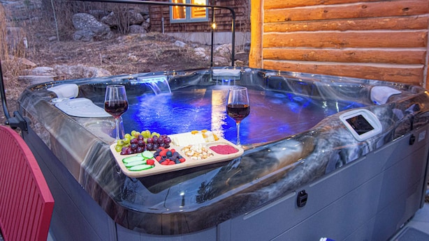 A hot tub with a tray of fruits and two glasses of wine. - Last Stand Pines is a charming cabin in Custer perfect for family getaways (Custer)