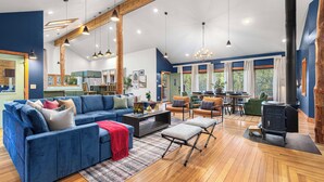 A spacious living area with a blue sofa, wooden flooring, and a black wood-burning stove. - Last Stand Pines is a charming cabin in Custer perfect for family getaways (Custer)