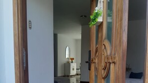 Ein Flur, der in einen Wohnbereich mit einer Couch, einem Schrank und einem dekorativen Spiegel führt.