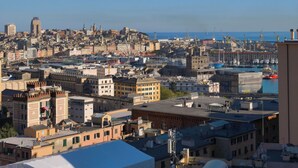 A cityscape with a mix of historic and modern buildings, a harbor with boats, and a clear blue sky. - Casa Adamo- Rooftop Hideaway (Genova)
