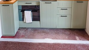 A compact kitchen with a wooden countertop, a built-in oven, a sink, and light green cabinets. - Casa Adamo- Rooftop Hideaway (Genova)