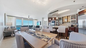 Een moderne woonkamer met een eethoek, keuken en grote ramen met uitzicht.