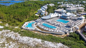 Ett flygbildsbild av ett semesterområde med flera pooler, ett stort byggnadskomplex och omgivande skogsområden.