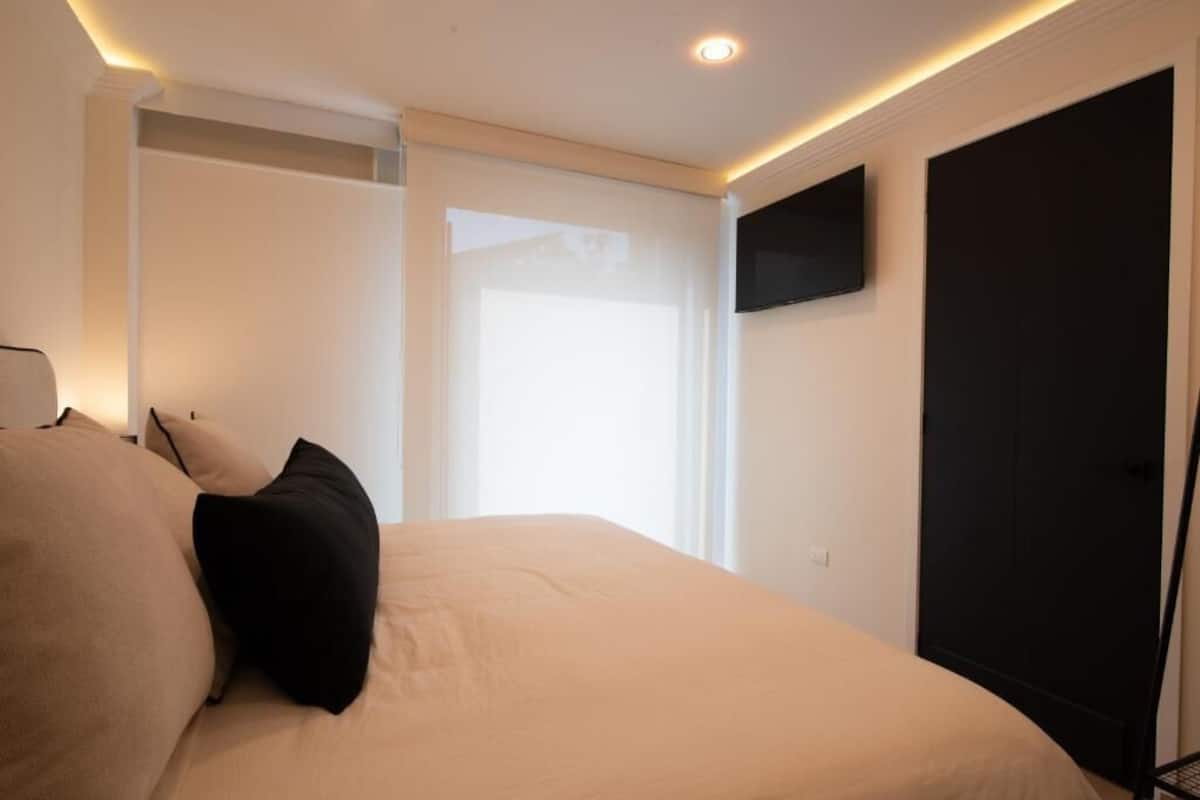 A bedroom with a bed, a TV mounted on the wall, and a sliding door.