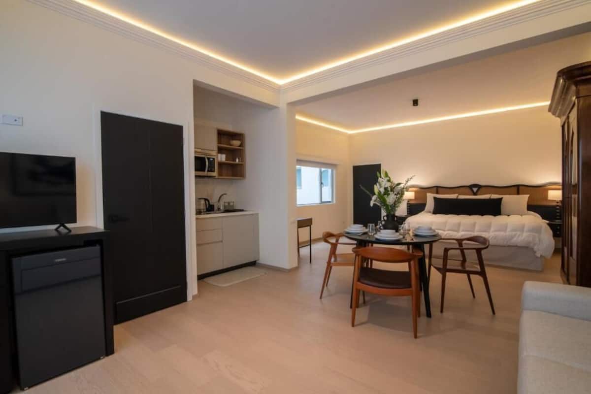 A compact hotel room with a kitchenette, a dining area, and a bed.