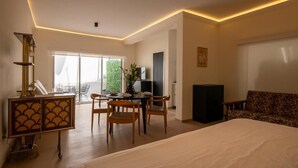 Ein modernes Hotelzimmer mit einem großen Bett, einem Essbereich mit Stühlen, einem Fernseher und einem Sofa.
