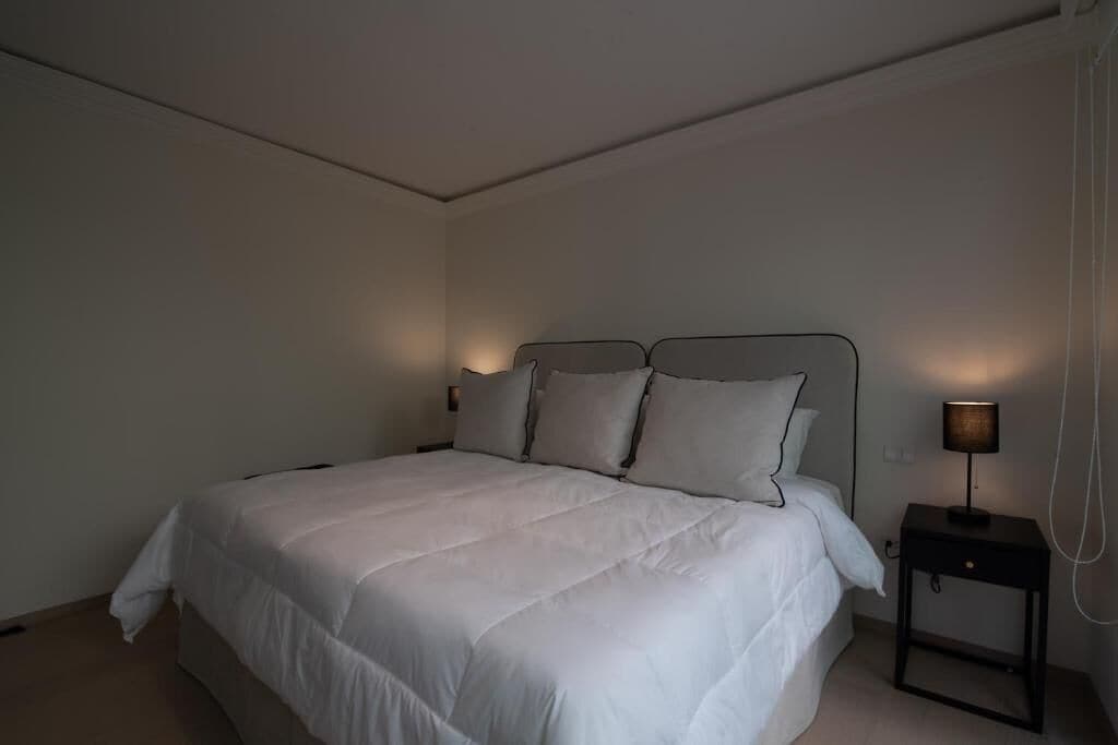A bedroom with a bed, bedside lamps, and a nightstand.