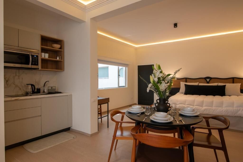Un espace de vie compact comprenant un coin cuisine, un coin repas et un lit avec une tête de lit.