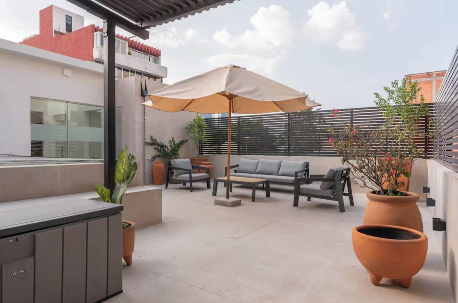 An outdoor patio with a sofa, chairs, a table, and a large umbrella.