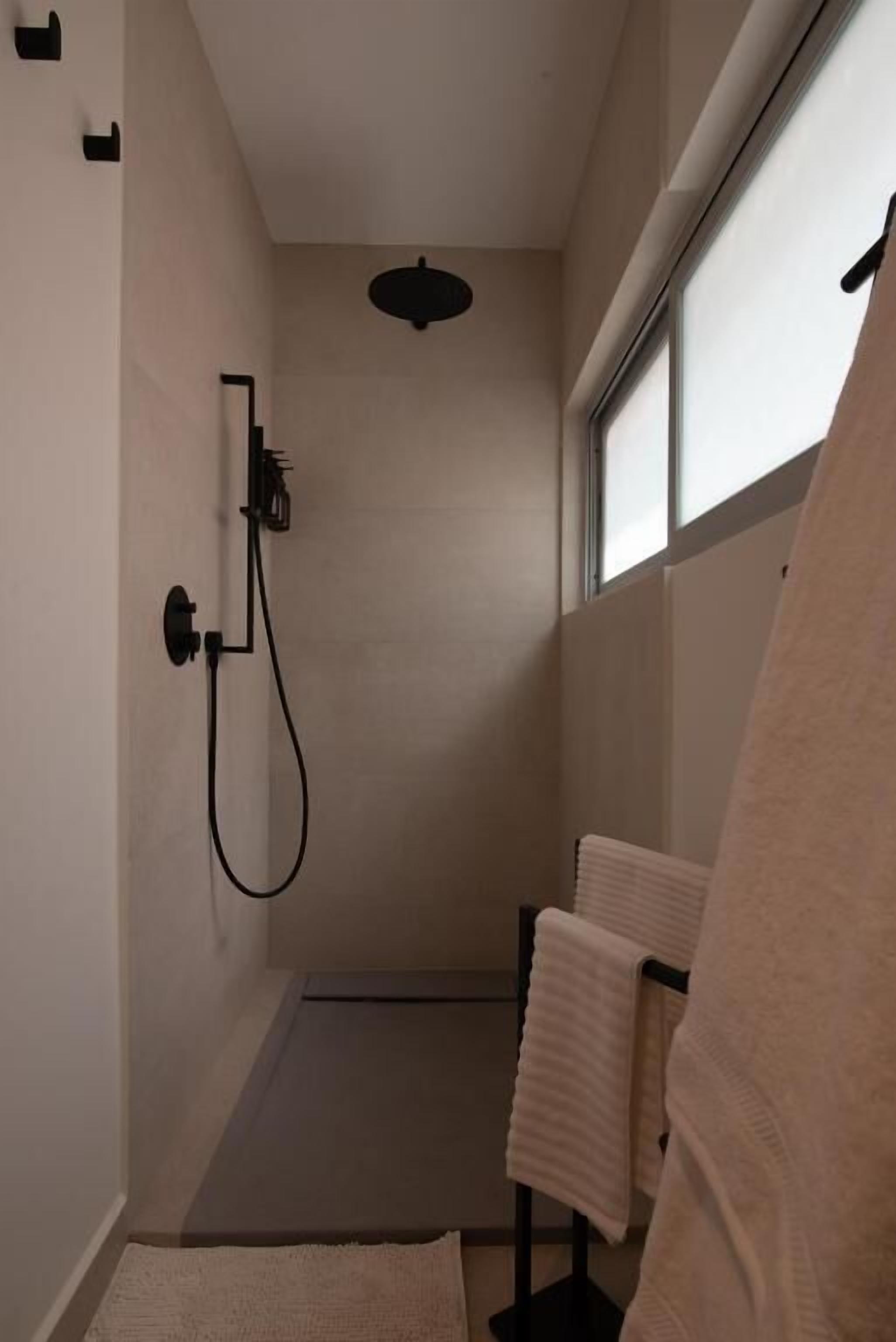 Un espacio de ducha moderno con panel de control, barra para toallas y ventana que proporciona luz natural.