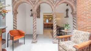Ein Innenraum mit einer zentralen Säule, einem Essbereich und einer Sitzecke mit einem gemusterten Sofa.
