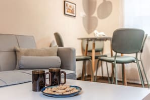 A living room with a sofa, a dining table with chairs, and a plate of cookies. - Heart of the City - Rest & Recharge (Great Yarmouth)