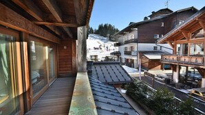 A wooden balcony with a view of a snowy mountain and a bar area. - Wifi, 100m from ski slopes, 1st floor, balcony, tv, ski locker, 81m², Les Gets (Les Gets)