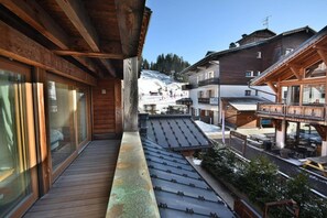 Ein Holzbalkon mit Blick auf einen verschneiten Berg und eine Bar.