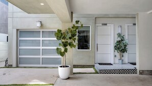 Un bâtiment moderne doté d’une porte de garage, d’une plante en pot et d’un paillasson.